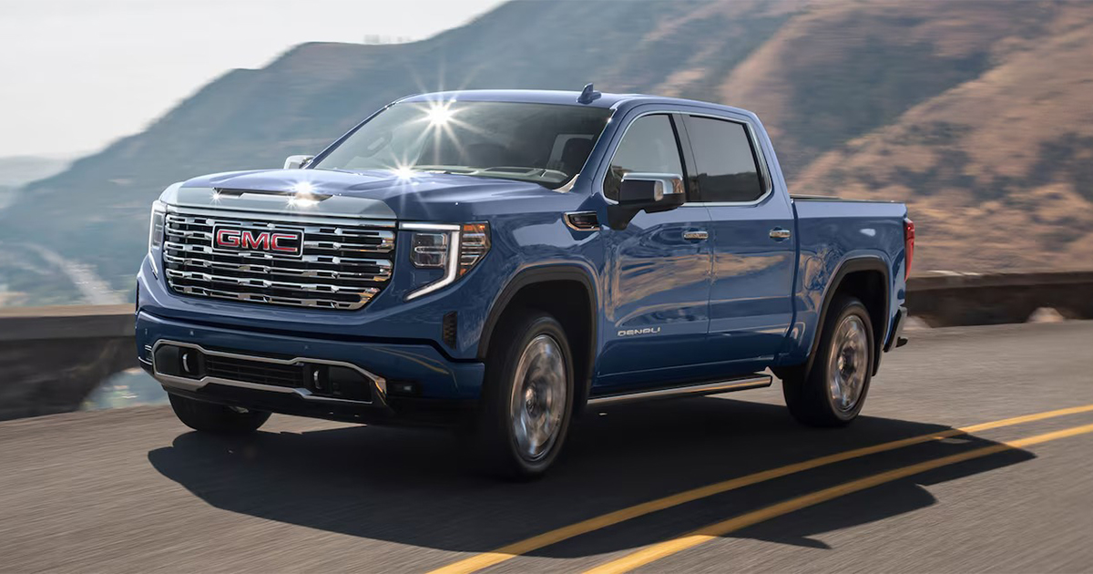 2025 GMC Sierra 1500 Denali pickup truck in blue driving on mountain highway showcasing premium styling