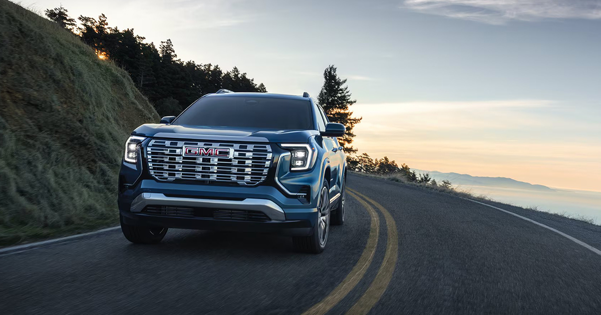 Blue 2026 GMC Terrain driving on winding mountain road demonstrating handling and performance