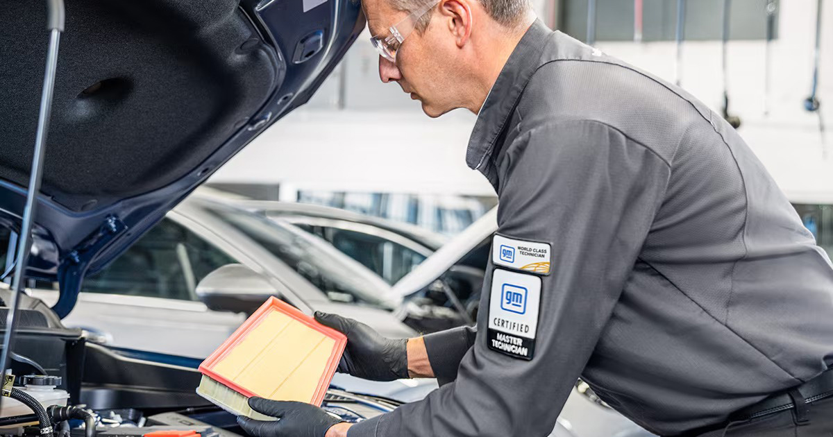 GM certified technician replacing air filter during Buick vehicle maintenance service
