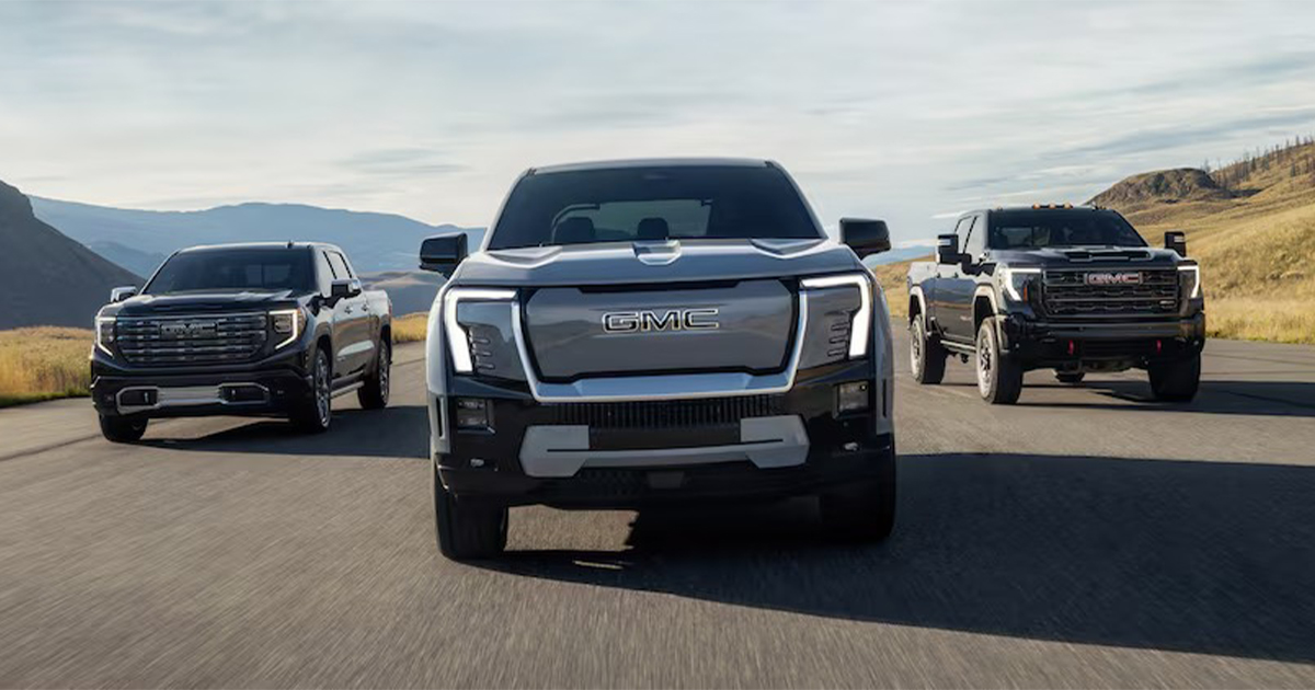 Three GMC vehicles including Sierra EV electric pickup truck leading convoy on mountain highway